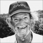 black and white image of Arthur Steinberg, a white man sporting a baseball cap, with salt and pepper hair and beard and with a big smile.